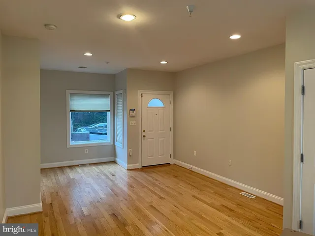 a view of an empty room with wooden floor and closet
