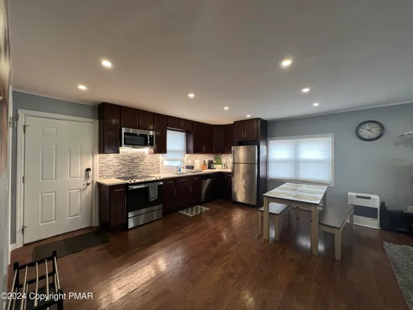 a kitchen with kitchen island stainless steel appliances sink cabinets and wooden floor