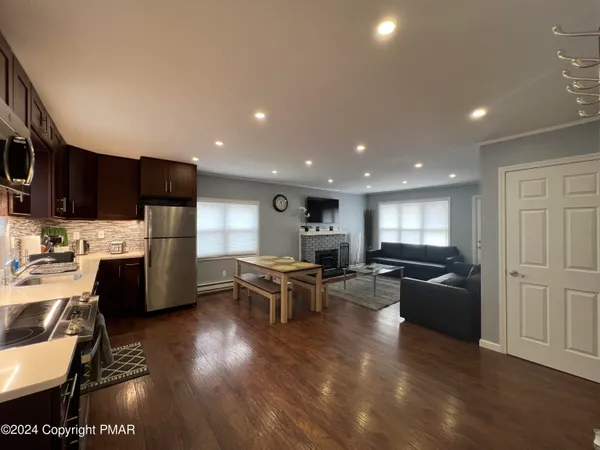 a living room with stainless steel appliances furniture and a view of kitchen
