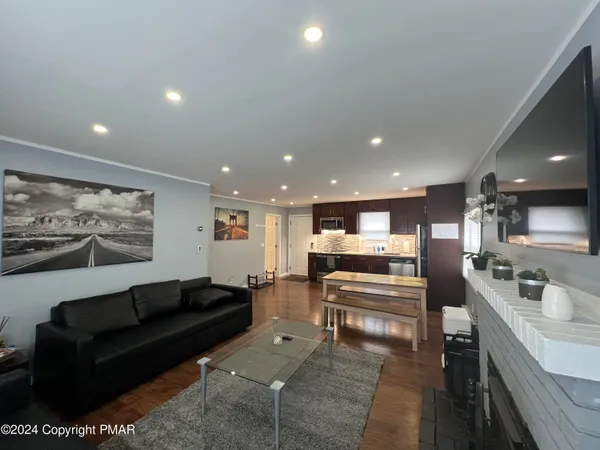 a living room with stainless steel appliances furniture and kitchen view