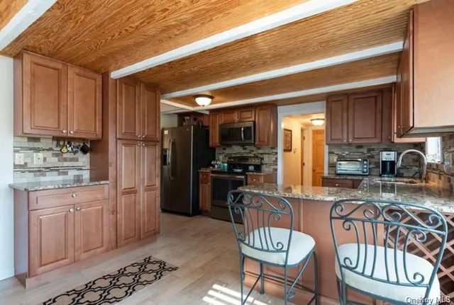 a kitchen with stainless steel appliances granite countertop a refrigerator a stove a sink dishwasher and white cabinets with wooden floor