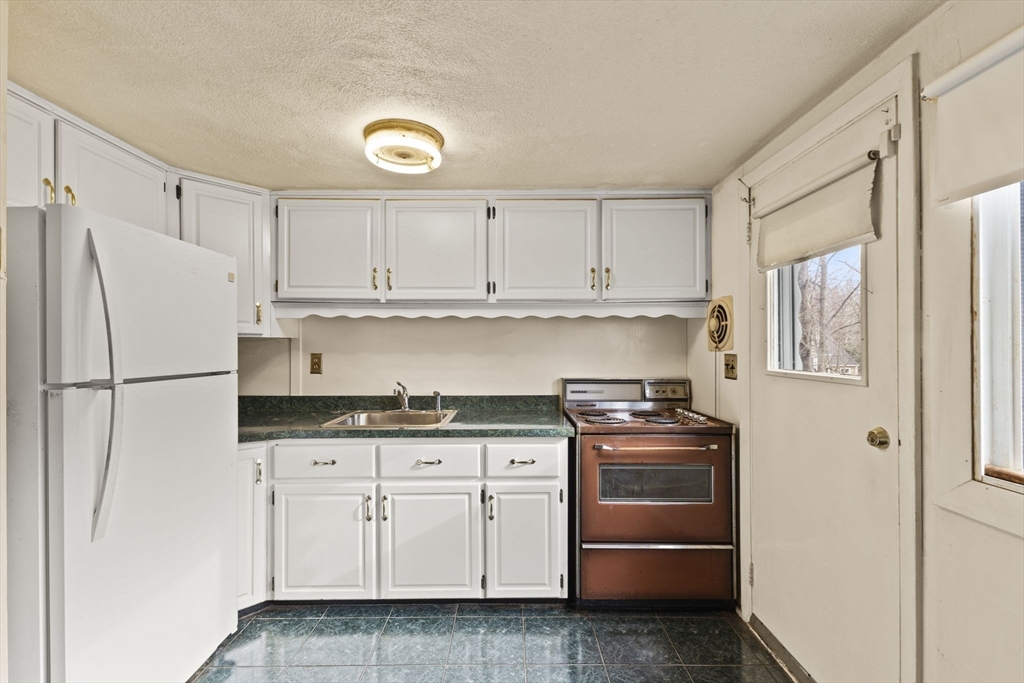 2 Alwin Street Boston, MA 02136 - Photo 16 of 43 a kitchen with granite countertop a refrigerator stove and white cabinets