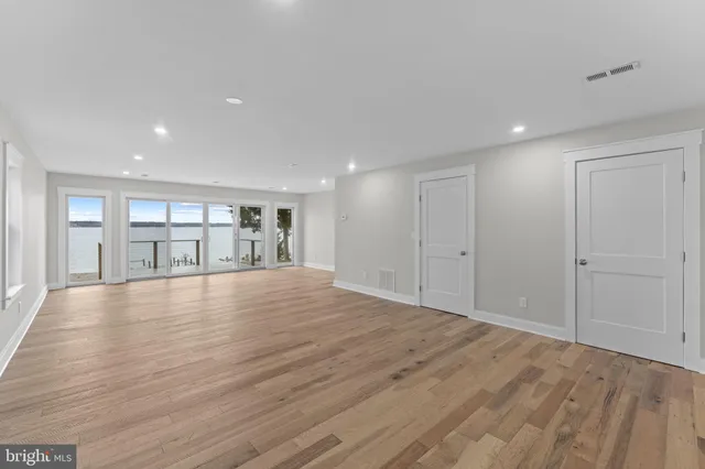 a big room with wooden floor and a kitchen view