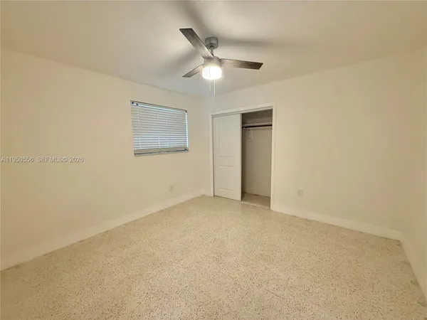 an empty room with a ceiling fan and a window