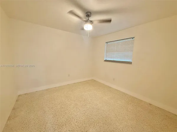 an empty room with a ceiling fan and window