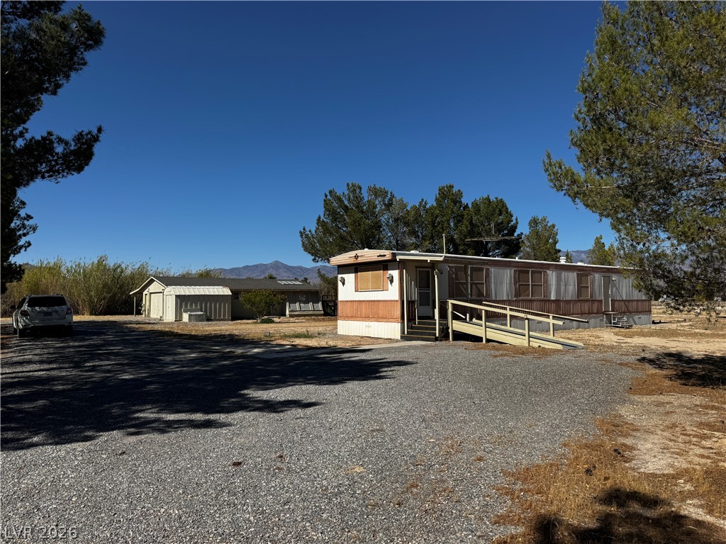 3090 Gally Road Pahrump, NV 89060 - Photo 4 of 20 A manufactured home with an accessibility ramp sits on a gravel lot under a clear sky.