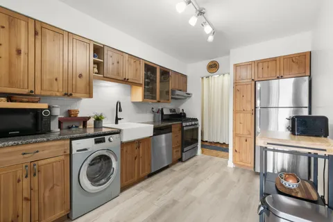 a kitchen with stainless steel appliances granite countertop a refrigerator a stove top oven a sink and dishwasher with wooden floor