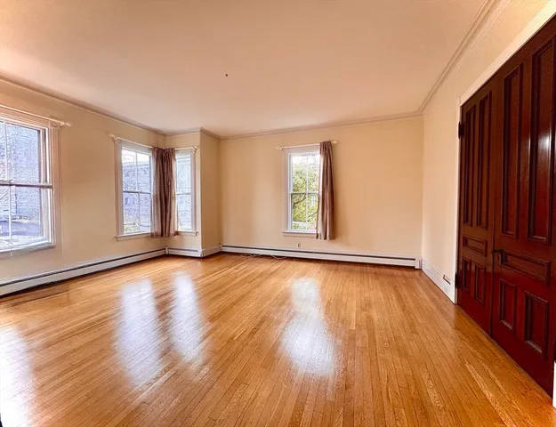 a view of an empty room with wooden floor and a cabinet