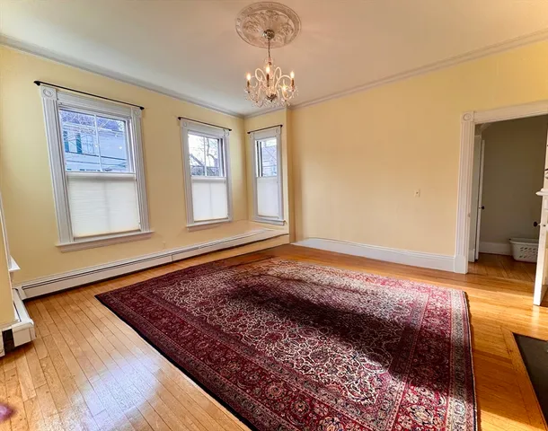 a view of a hallway to room with wooden floor and window