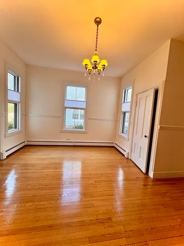 a view of empty room with wooden floor and chandelier