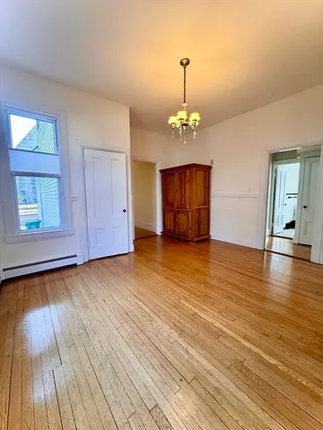 a view of an empty room with window and wooden floor