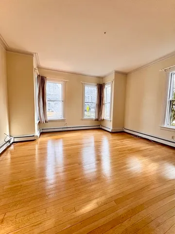 a view of an empty room with window and wooden floor