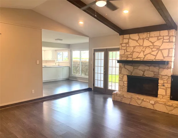 an empty room with wooden floor fire place and windows