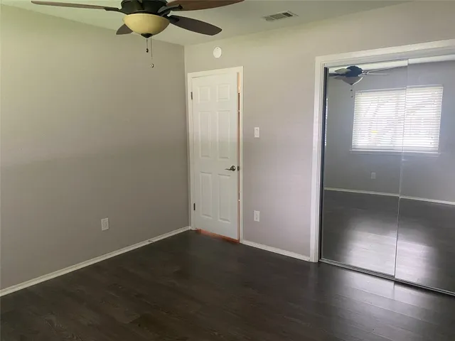 an empty room with wooden floor closet and windows
