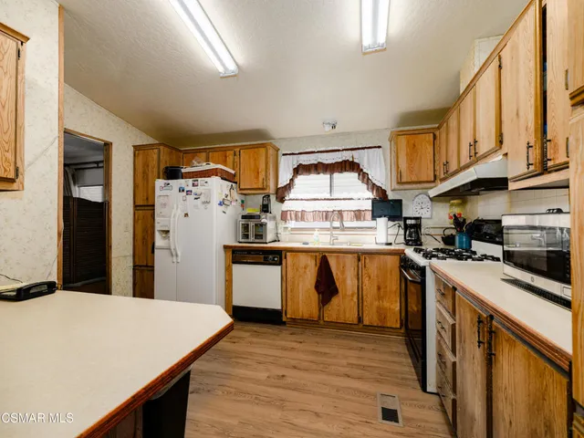 a kitchen with stainless steel appliances granite countertop a refrigerator a stove and a sink