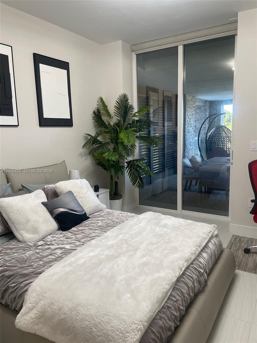 220 Southeast Mizner Boulevard, Unit 321 Boca Raton, FL 33432 - Photo 14 of 24 a bedroom with a bed large mirror and potted plant