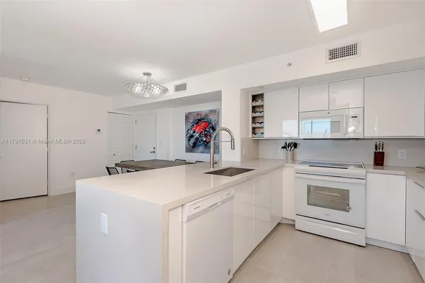 a view of a kitchen with kitchen island a sink appliances and a counter top space