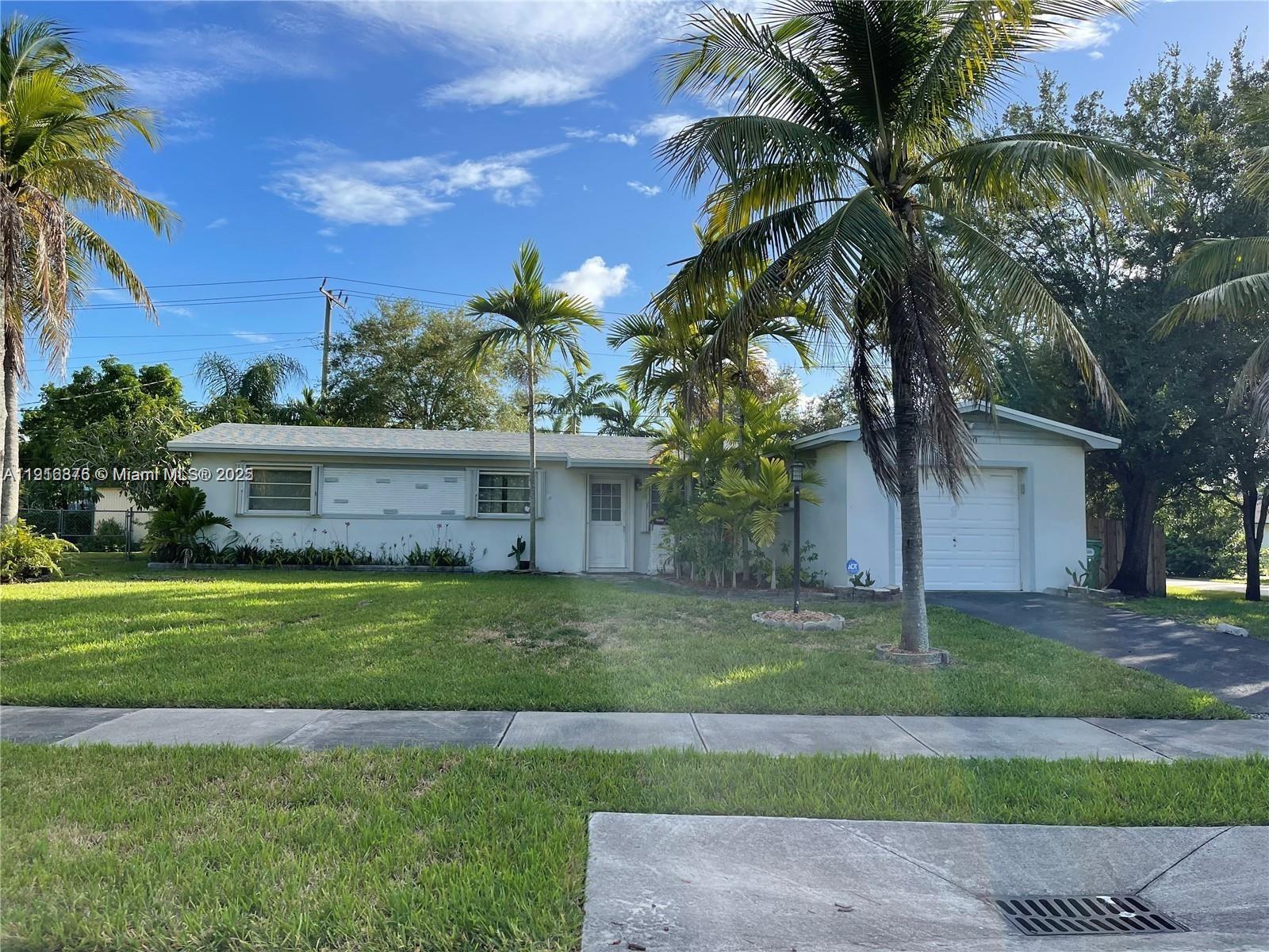 a front view of a house with a yard and palm trees