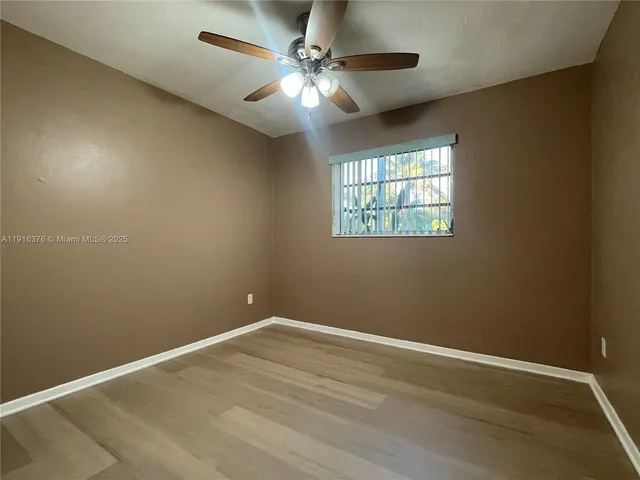 en empty room with windows and ceiling fan