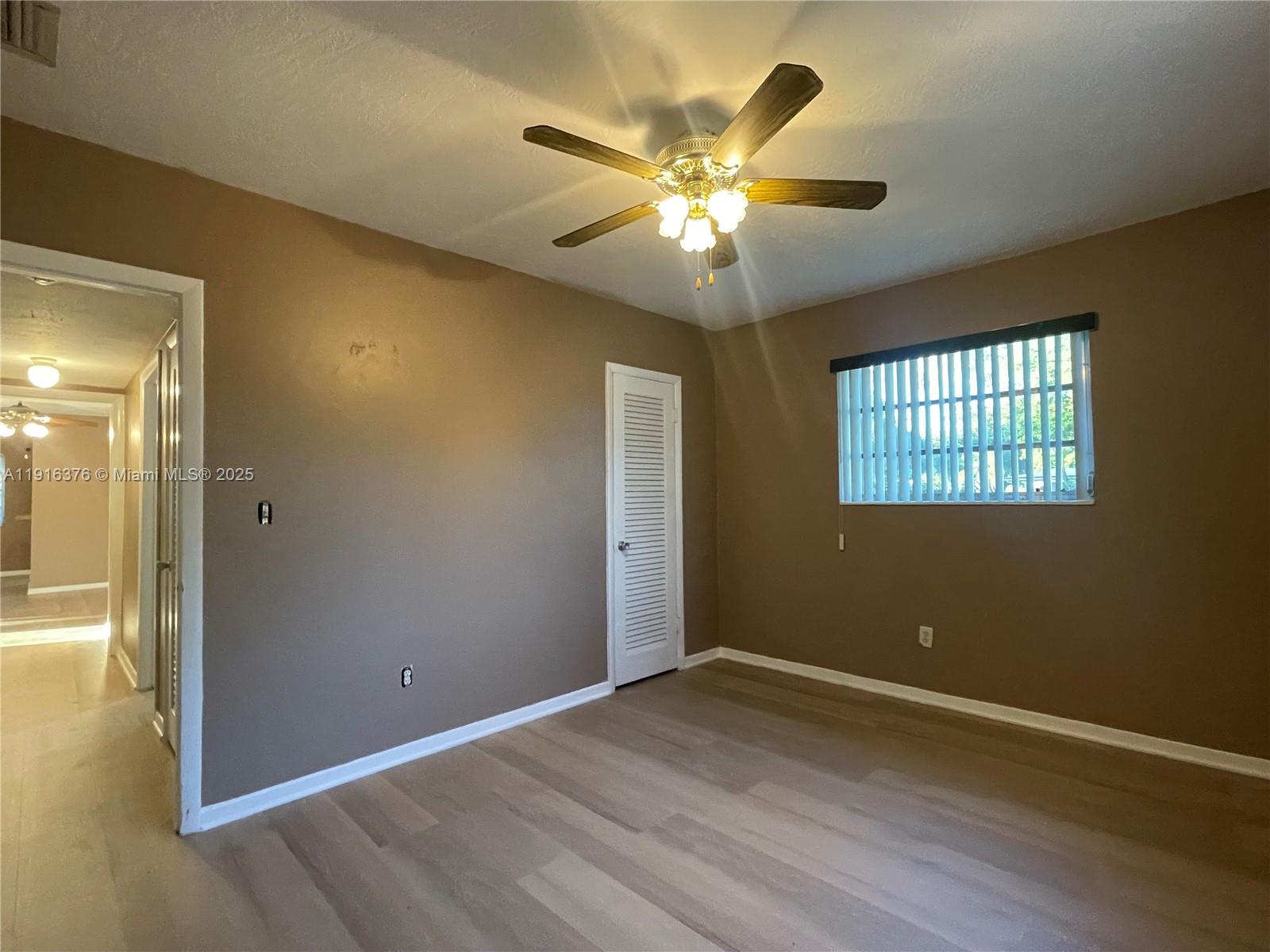 19700 Whispering Pines Road Cutler Bay, FL 33157 - Photo 13 of 27 an empty room with wooden floor closet and windows