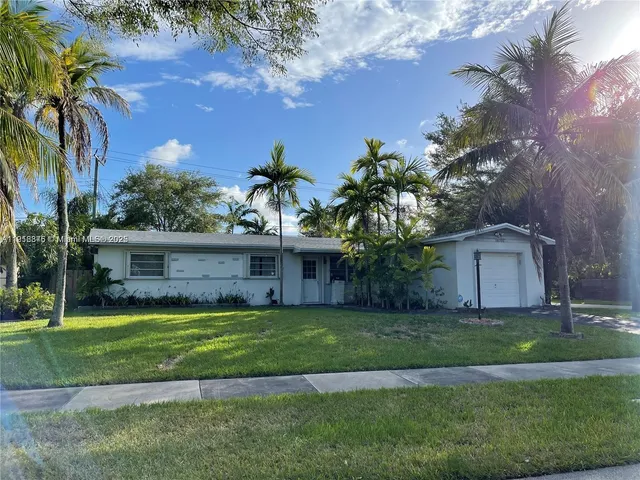 a view of a house with a yard and palm trees