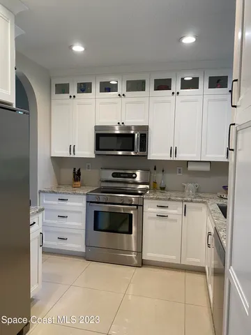 a kitchen with stainless steel appliances kitchen island granite countertop a stove top oven a sink and white cabinets