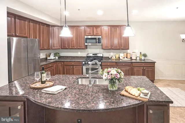 a kitchen with granite countertop a table chairs stove and refrigerator