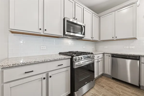 a kitchen with granite countertop white cabinets and stainless steel appliances