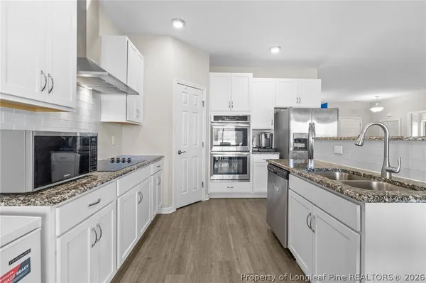 a kitchen with granite countertop white cabinets and white appliances