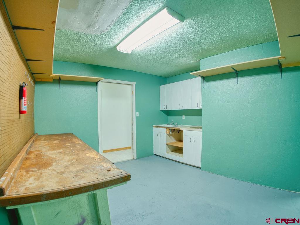 27980 Rd T Dolores, CO 81323 - Photo 22 of 29 Kitchen with concrete flooring, light countertops, a textured ceiling, white cabinetry, and open shelves