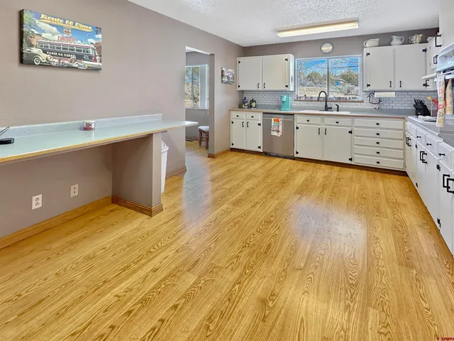 a large kitchen with stainless steel appliances wooden floors and view living room
