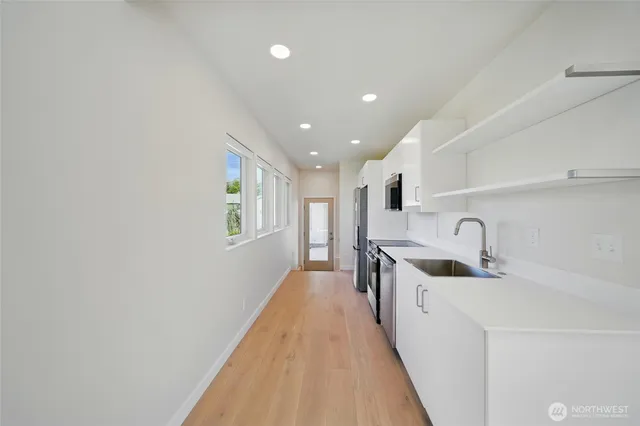 a view of a kitchen with a sink and dishwasher a refrigerator with white cabinets