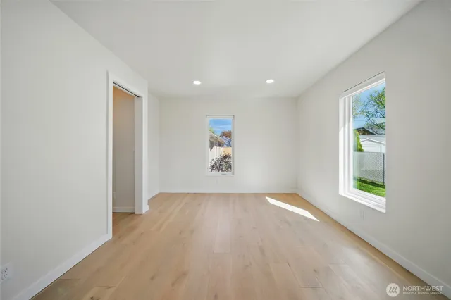 an empty room with wooden floor and windows