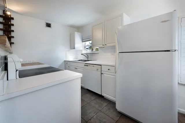 a kitchen with a refrigerator sink stove and white cabinets