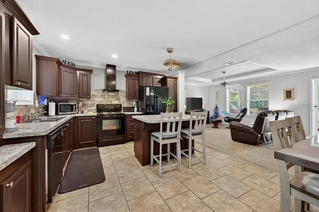 a kitchen with stainless steel appliances kitchen island granite countertop a table chairs and a refrigerator