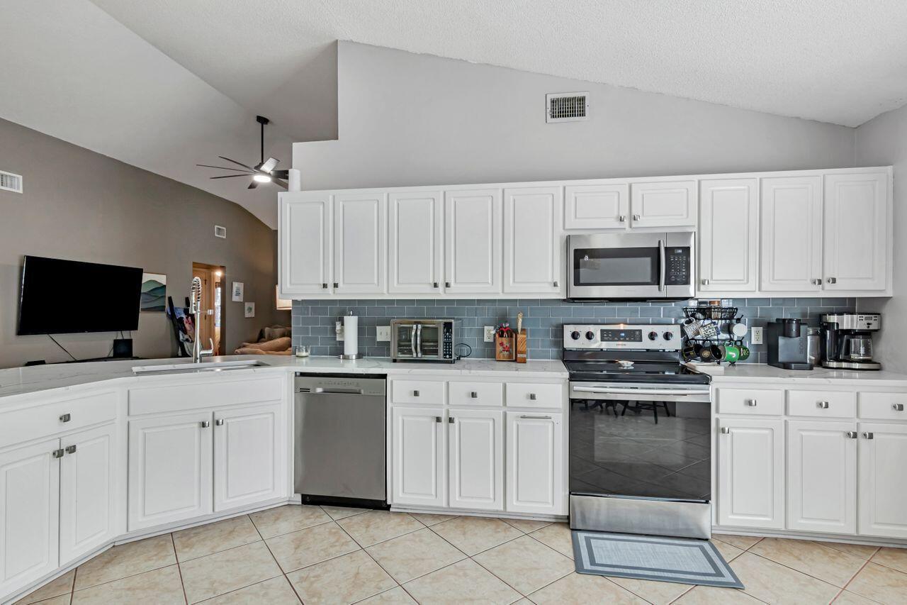 9761 Leeward Way Navarre, FL 32566 - Photo 12 of 43 a kitchen with white cabinets sink and stainless steel appliances