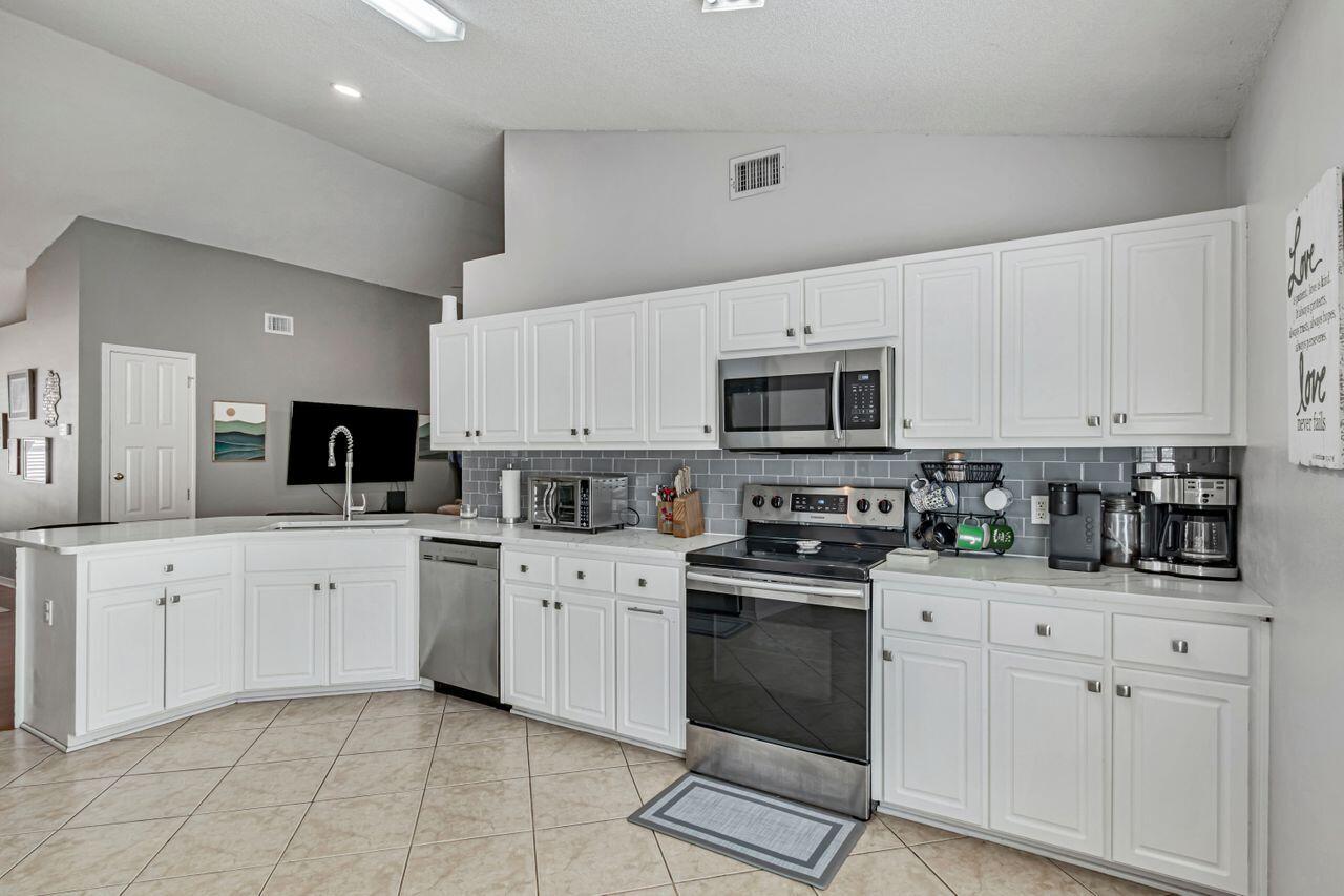 9761 Leeward Way Navarre, FL 32566 - Photo 13 of 43 a kitchen with white cabinets sink and stainless steel appliances