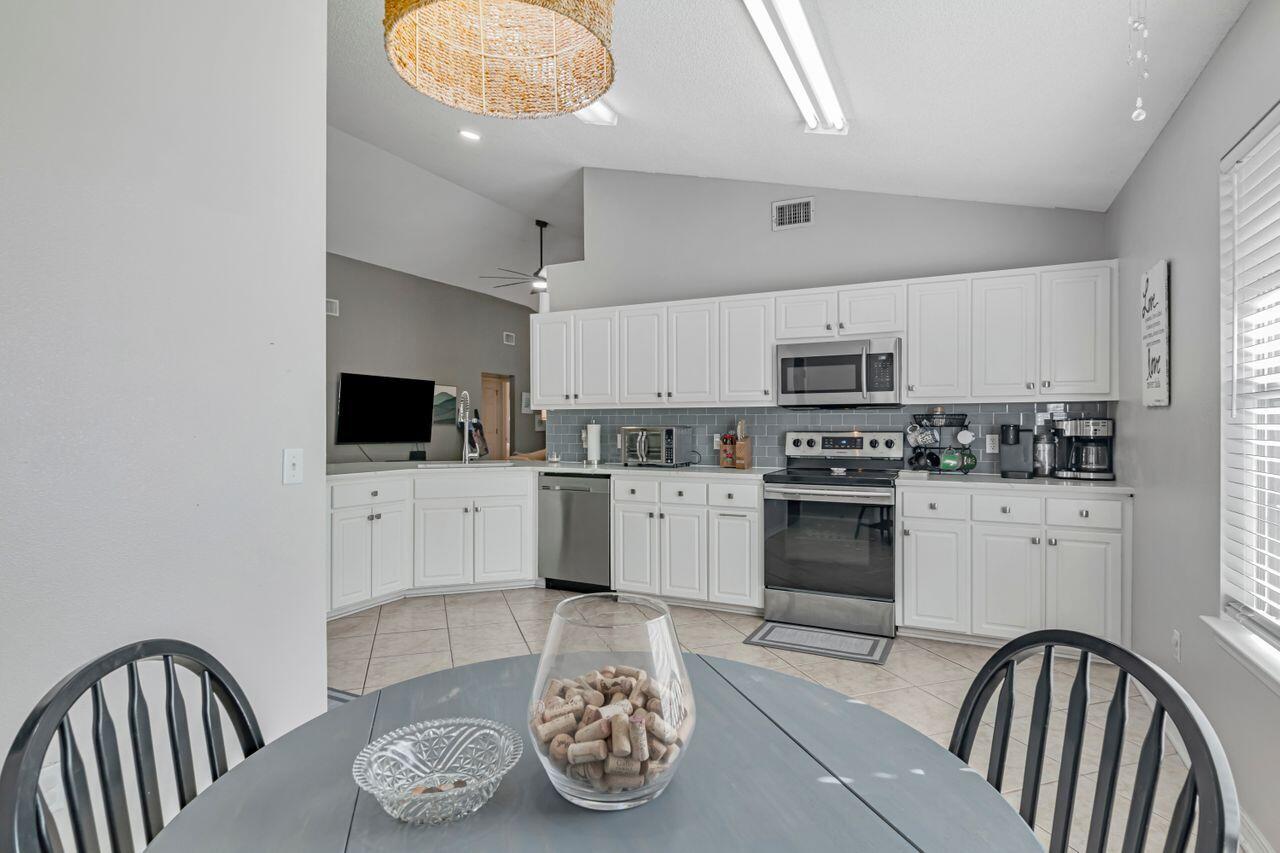 9761 Leeward Way Navarre, FL 32566 - Photo 15 of 43 a kitchen with stainless steel appliances a microwave a stove a sink dishwasher and white cabinets with wooden floor