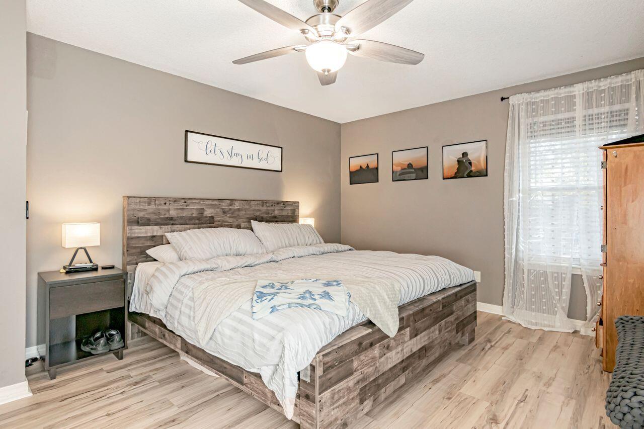 9761 Leeward Way Navarre, FL 32566 - Photo 25 of 43 a bedroom with a bed and a chandelier