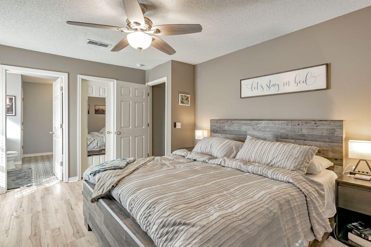 9761 Leeward Way Navarre, FL 32566 - Photo 26 of 43 a bedroom with a large bed and a chandelier
