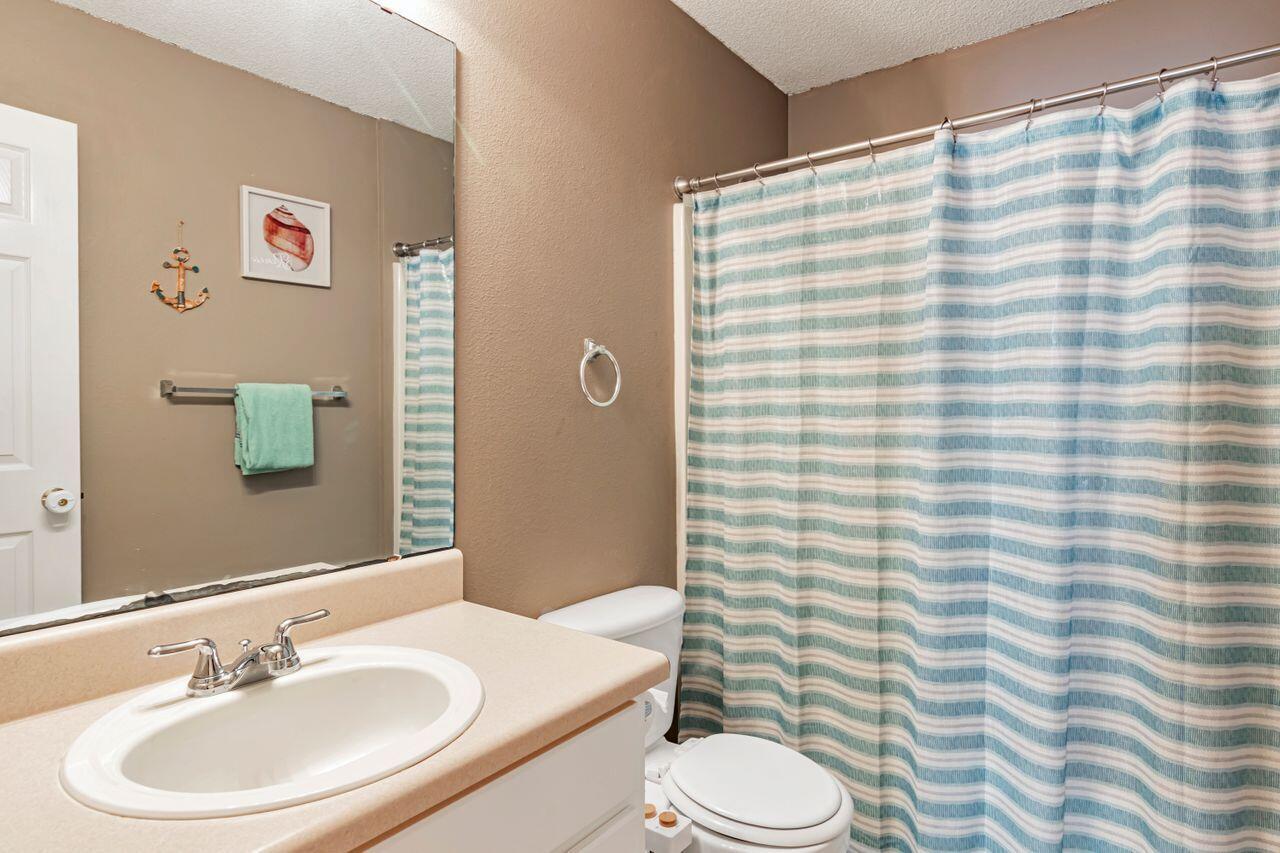 9761 Leeward Way Navarre, FL 32566 - Photo 31 of 43 a bathroom with a sink a toilet and shower curtain