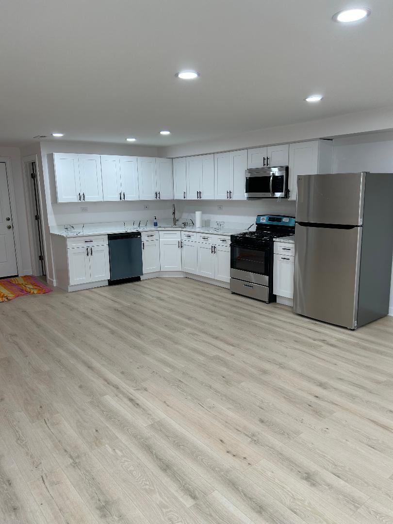 1439 West 16th Street, Unit 1 Chicago, IL 60608 - Photo 2 of 7 a large kitchen with stainless steel appliances a large counter top a stove and a refrigerator
