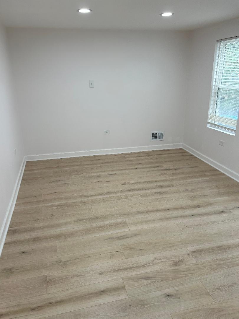 1439 West 16th Street, Unit 1 Chicago, IL 60608 - Photo 7 of 7 a view of an empty room with wooden floor and a window
