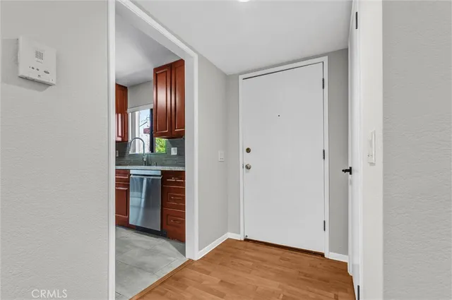 a view of an empty room with kitchen and a window