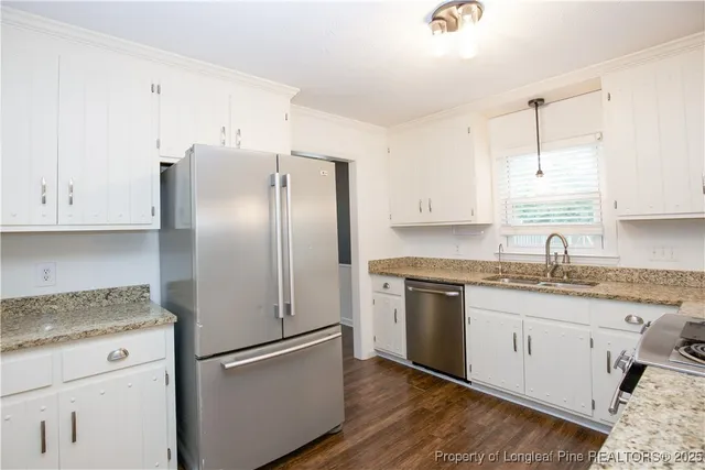 a kitchen with stainless steel appliances granite countertop a refrigerator sink and white cabinets
