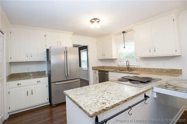 a kitchen with granite countertop a sink stove and refrigerator