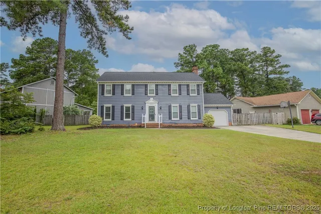 a front view of house with yard and trees in the background