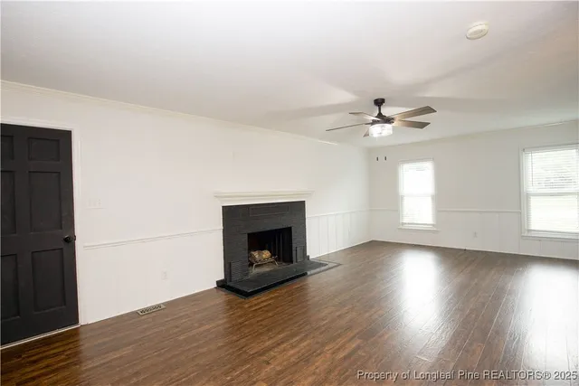 an empty room with wooden floor fireplace and windows