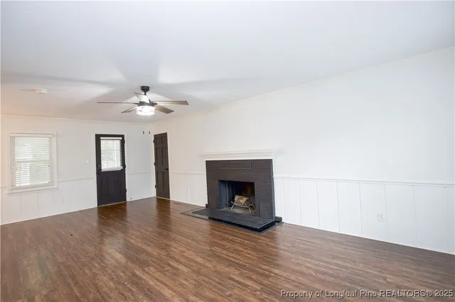 an empty room with wooden floor chandelier and fireplace