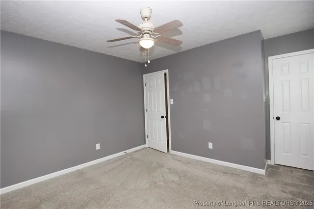 an empty room with a chandelier fan and windows